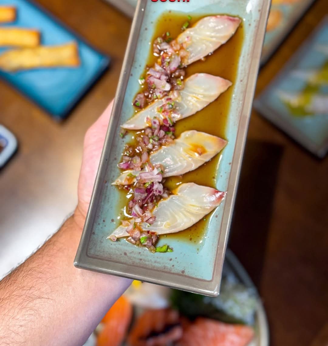 Carpaccio de peixe branco com cebola roxa num prato alongado