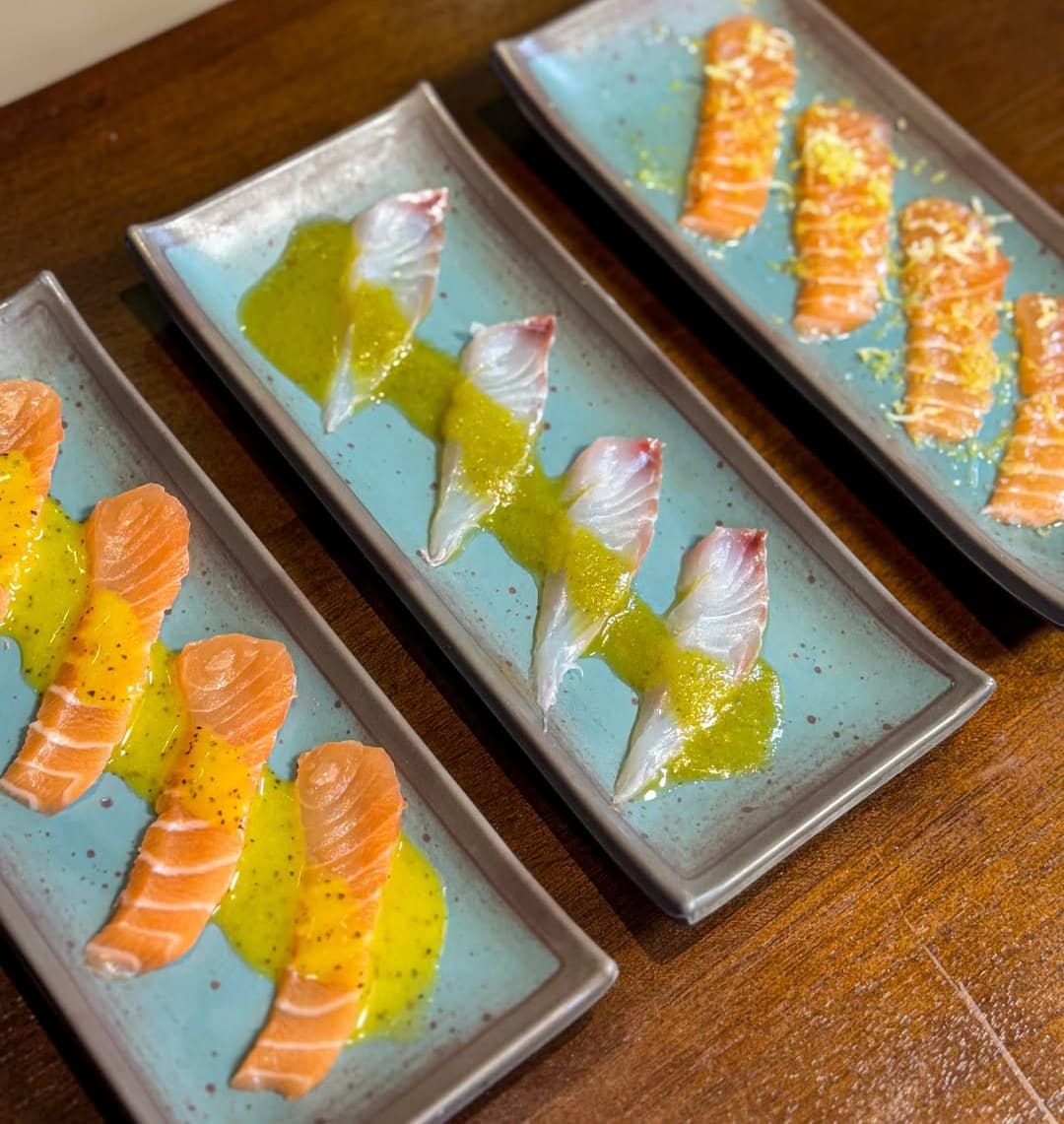 Fileira de carpaccios de salmão com molho em pratos azuis
