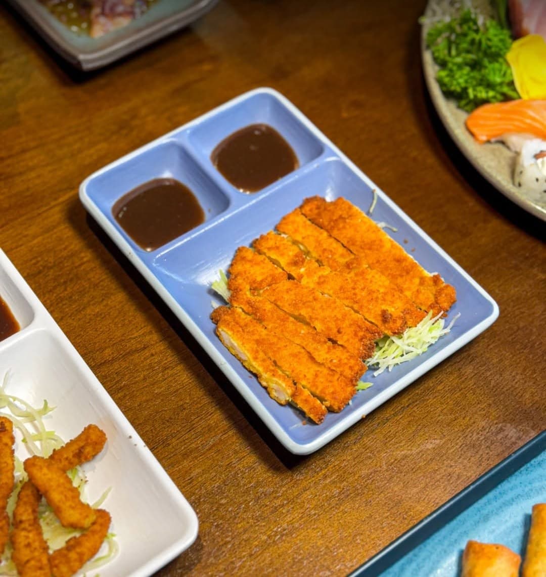 Chickenkatsu fatiado num prato azul com molho à parte