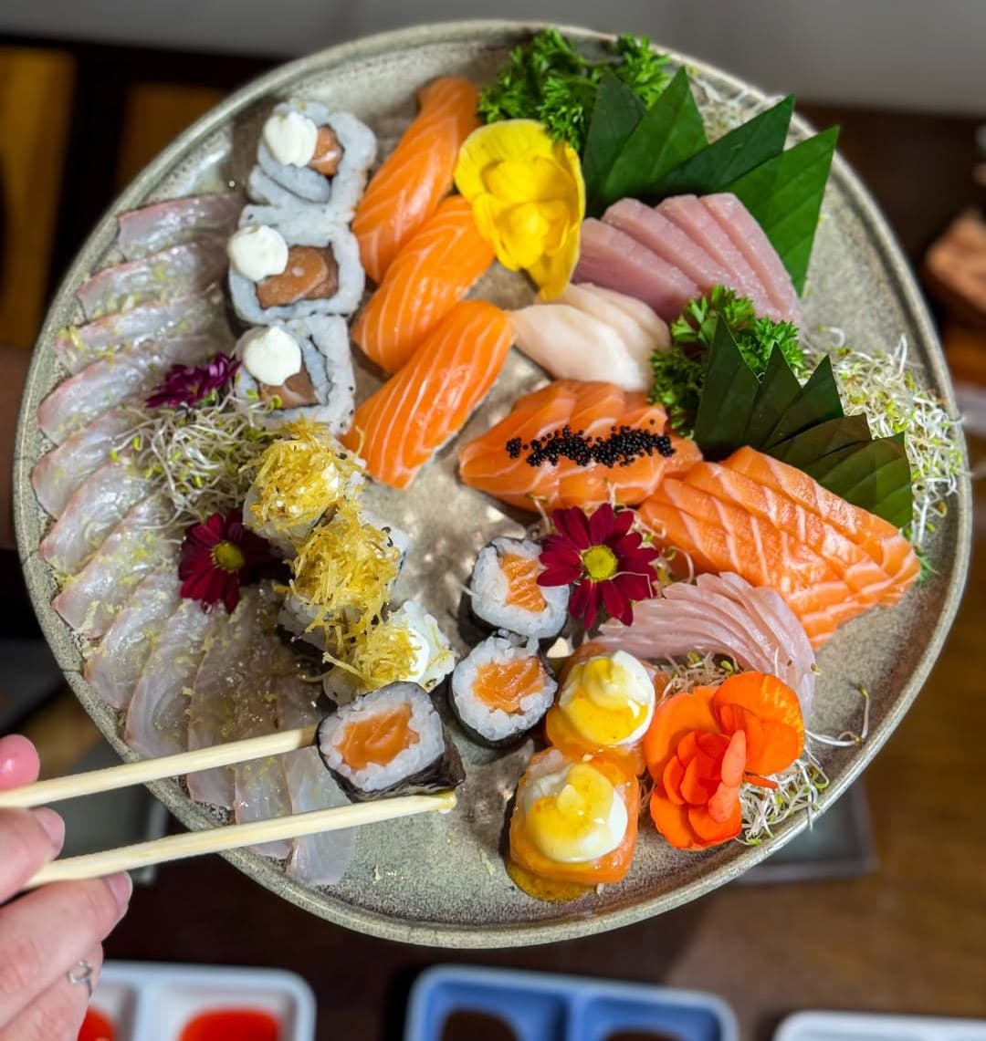 Mão com hashis pegando um sushi do combinado