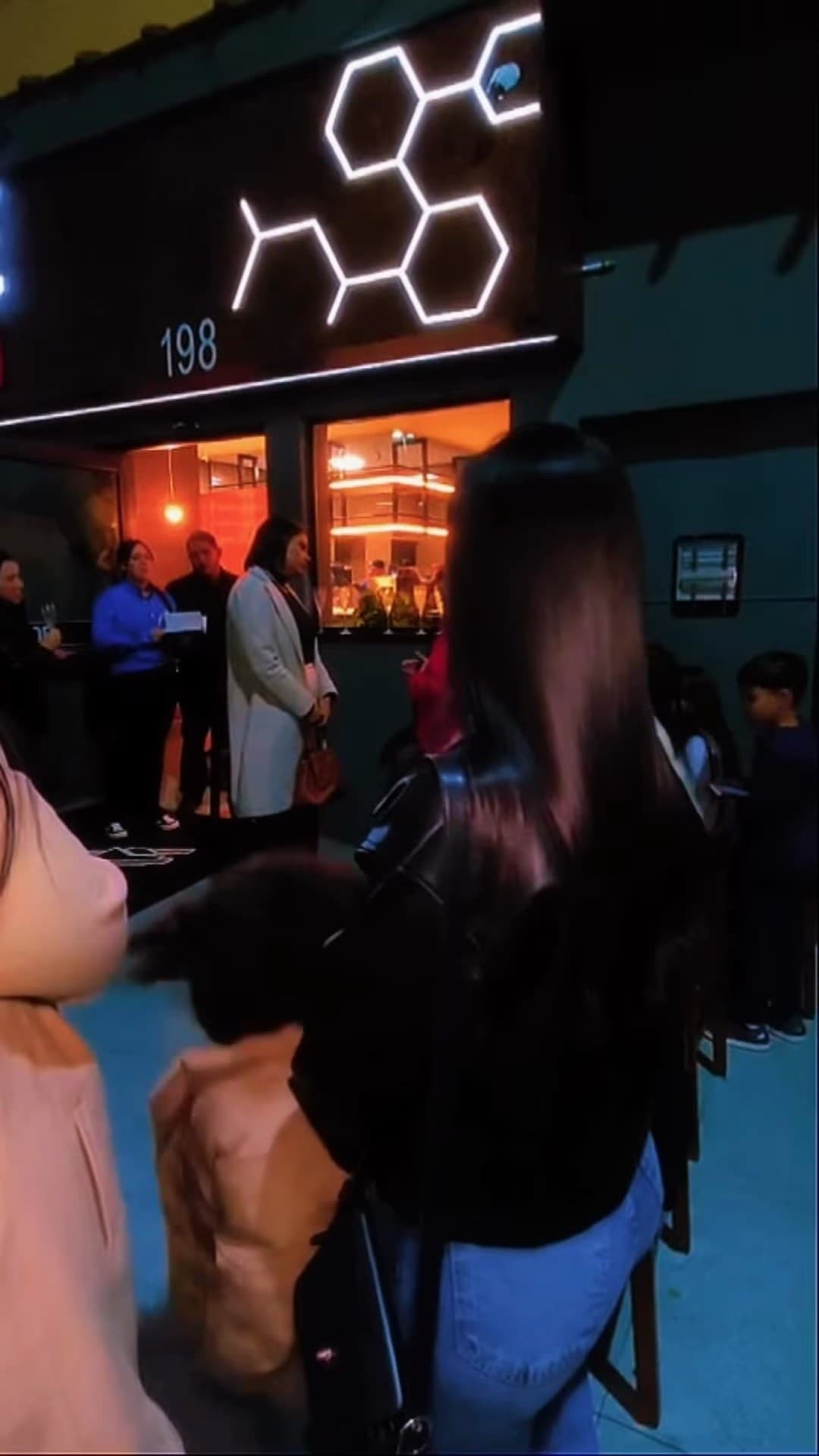 O número 198 e o neon em hexágonos na fachada, à noite