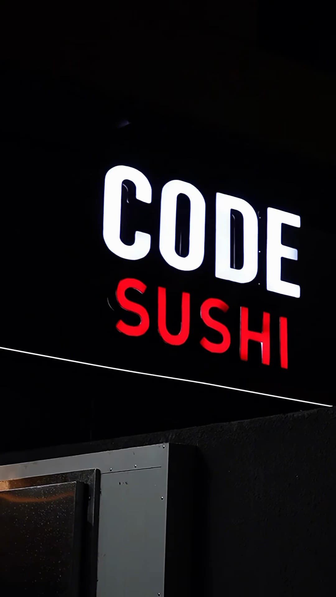 O letreiro luminoso CODE SUSHI aceso à noite