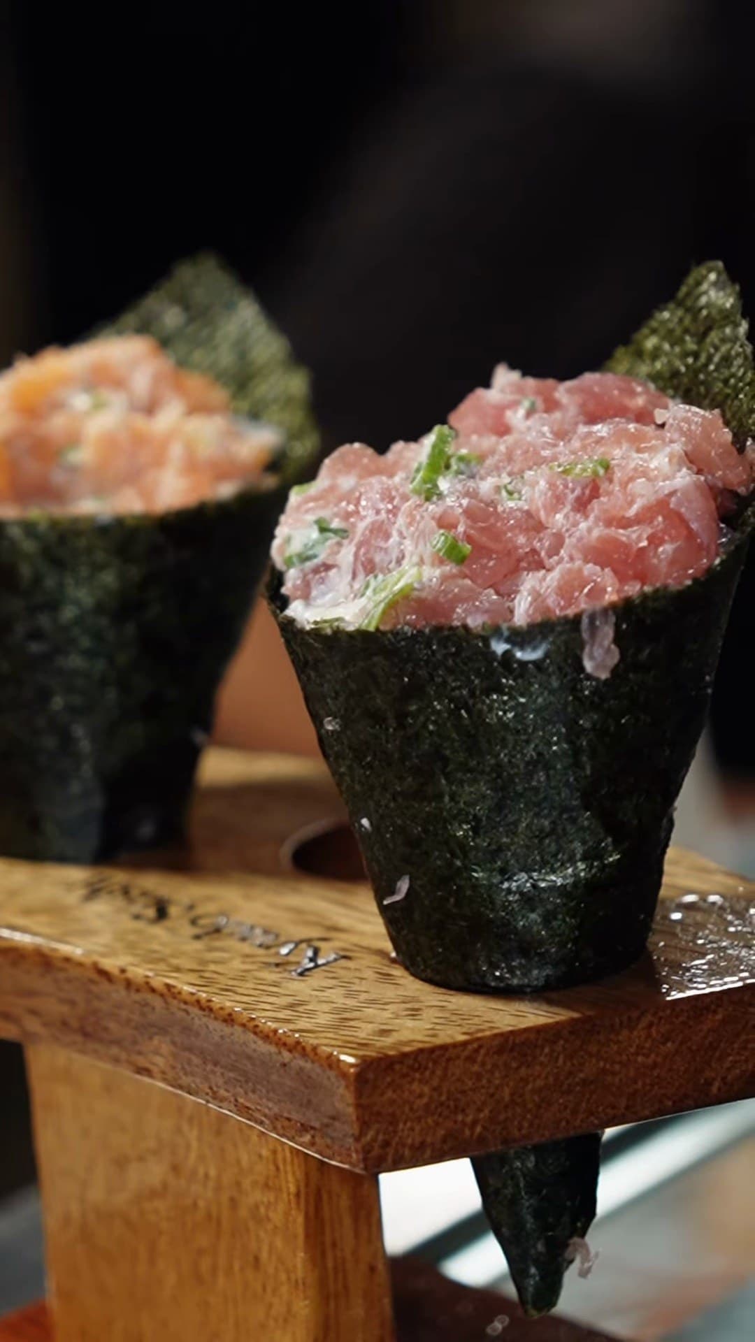 Temaki de atum em primeiro plano no suporte de madeira